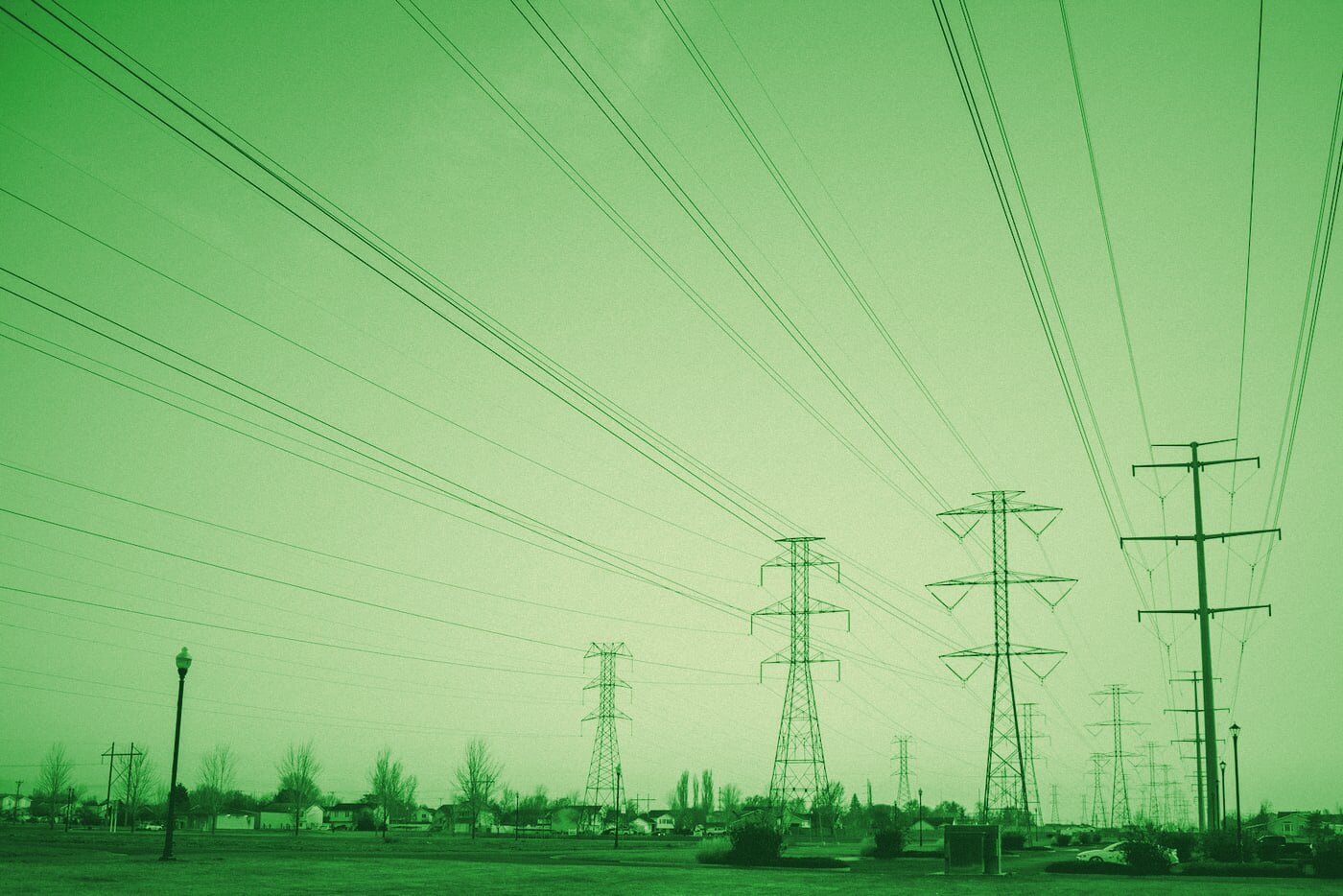 High-voltage electricity transmission lines strung between steel pylons against an open sky.