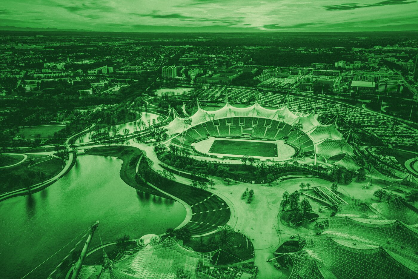 Aerial view of the sweeping tensile roof structure of a large civic stadium.